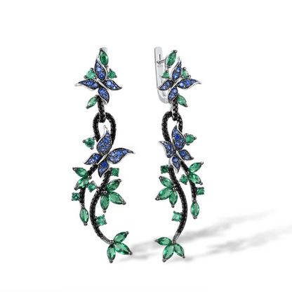 Long silver earrings with blue and green crystal butterflies and vine-like detailing

