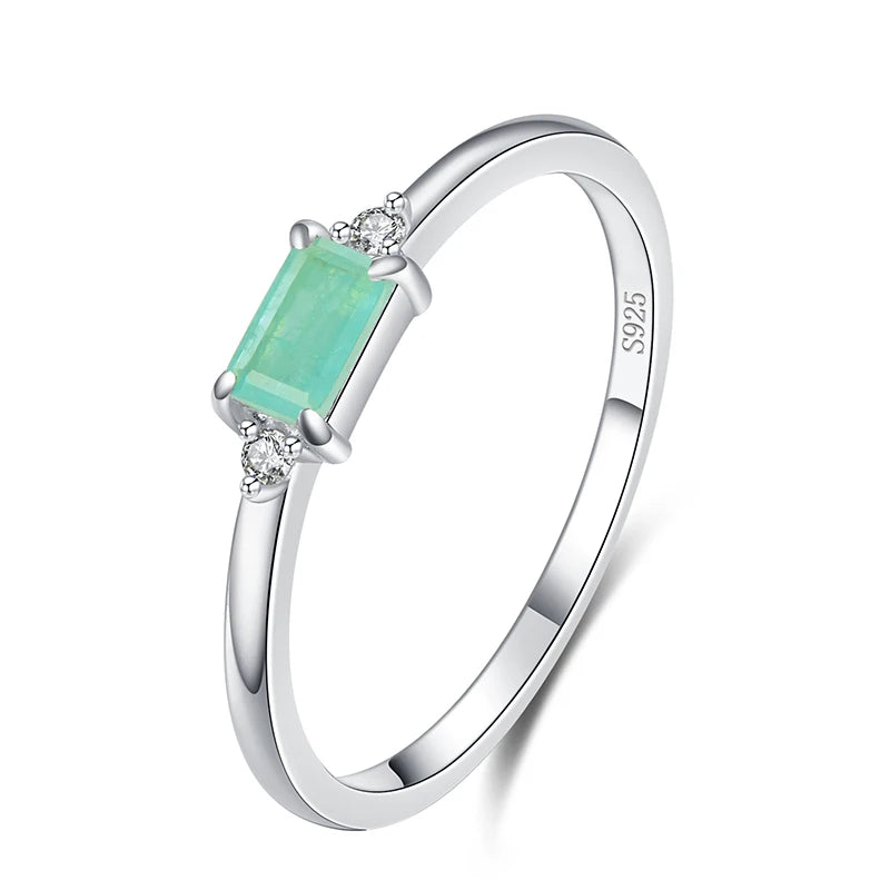 Delicate gold ring with a rectangular light green stone and two small clear side stones.

