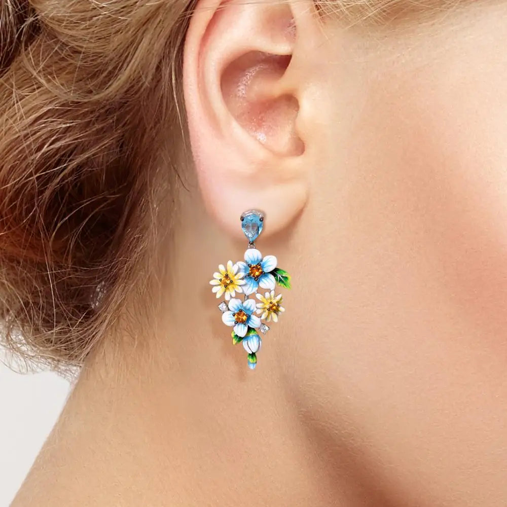 Sterling silver floral drop earrings with blue enamel flowers and orange gemstone centers

