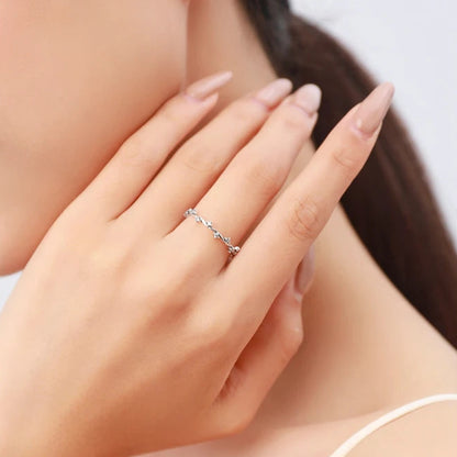 Delicate silver ring with twisting vine-like structure and small clear stones


