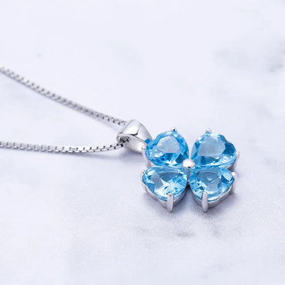 Silver pendant featuring four heart-cut light blue stones arranged in a floral shape


