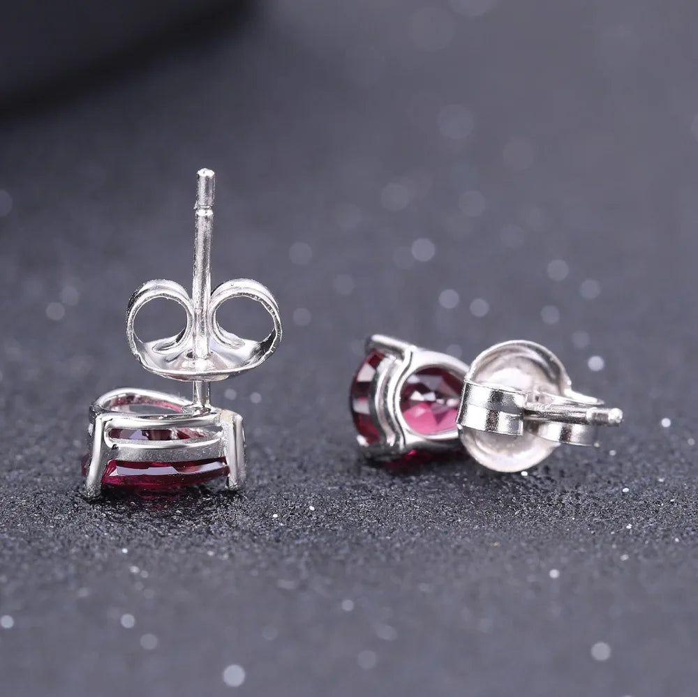 Pear-cut red gemstone stud earrings set in silver-tone prongs.

