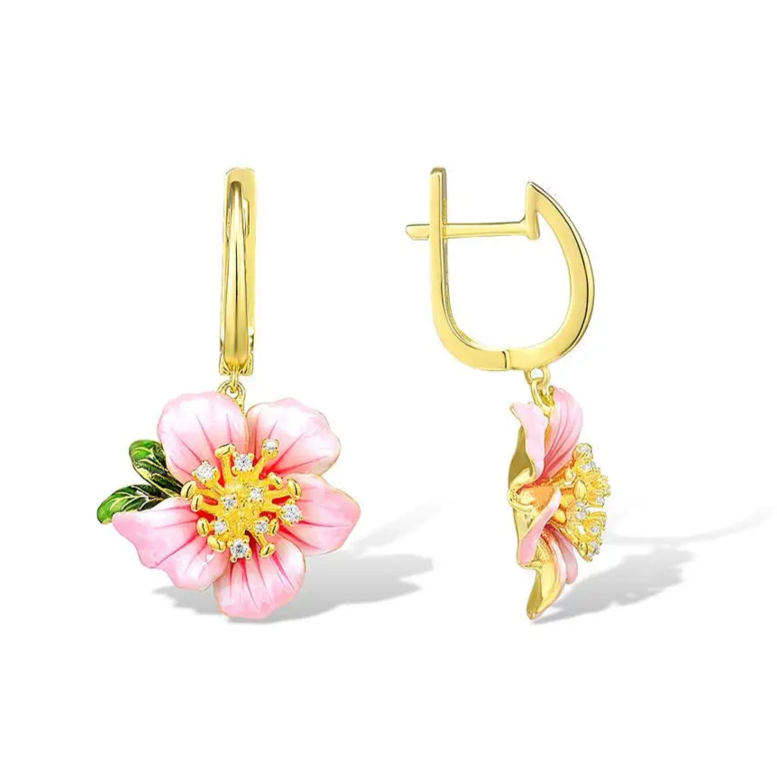 Prato earrings featuring soft pink flower petals, golden centers with crystal accents, and green enamel leaves.

