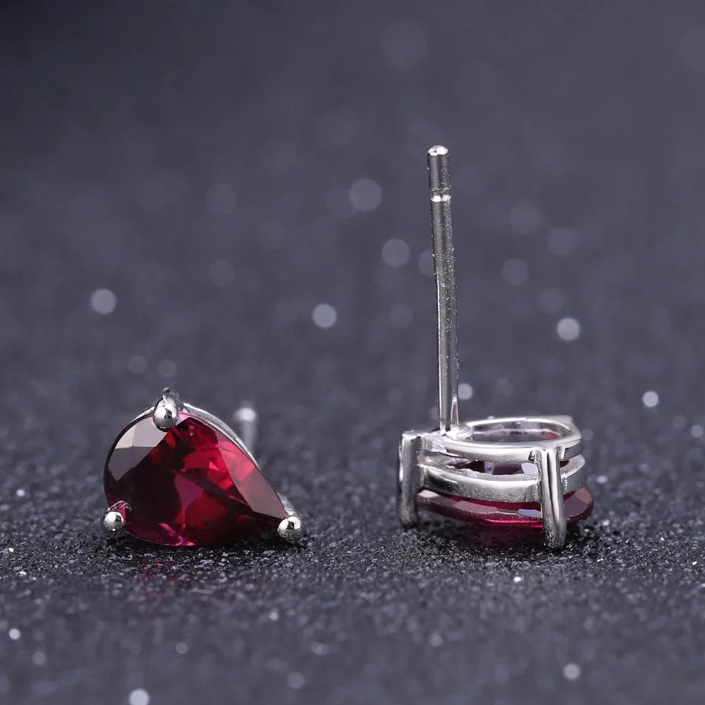 Pear-cut red gemstone stud earrings set in silver-tone prongs.

