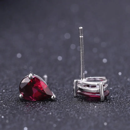 Pear-cut red gemstone stud earrings set in silver-tone prongs.

