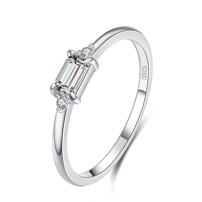 Delicate gold ring with a rectangular light green stone and two small clear side stones.

