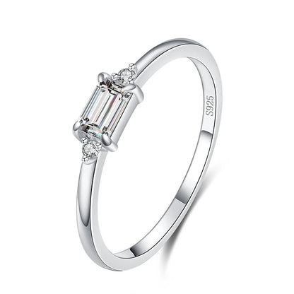 Delicate gold ring with a rectangular light green stone and two small clear side stones.

