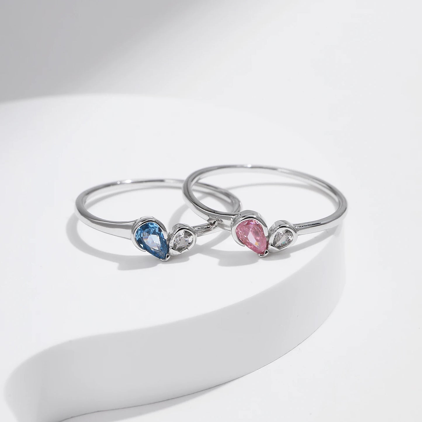 Sterling silver ring with a pear-shaped blue stone and round white stone set side by side
Sterling silver ring featuring a pink teardrop stone paired with a round clear stone in an open-heart inspired setting.



