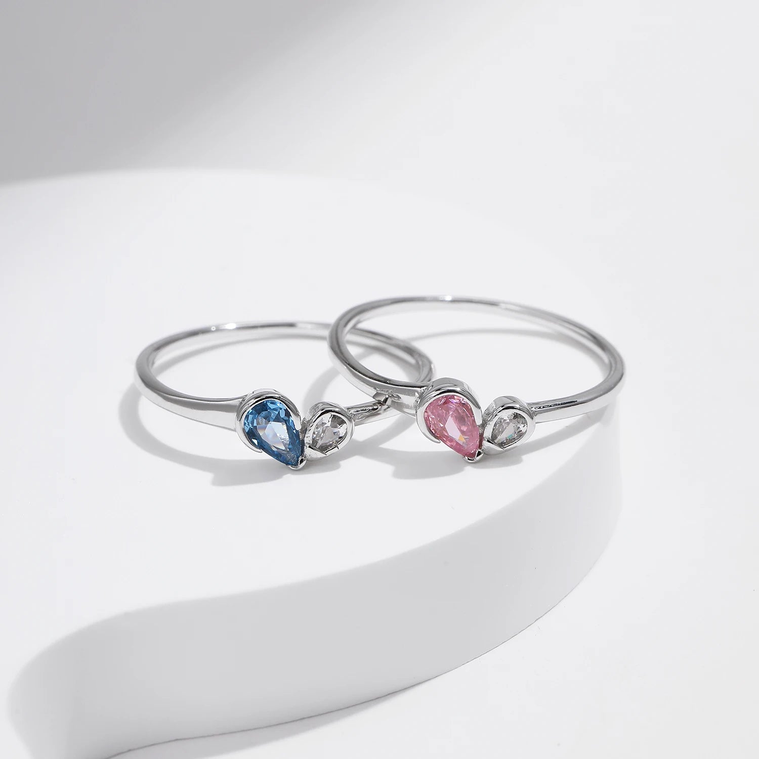 Sterling silver ring with a pear-shaped blue stone and round white stone set side by side
Sterling silver ring featuring a pink teardrop stone paired with a round clear stone in an open-heart inspired setting.



