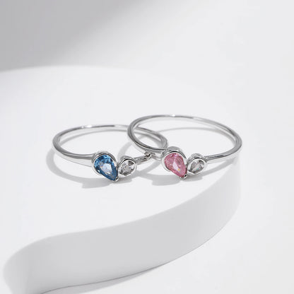 Sterling silver ring with a pear-shaped blue stone and round white stone set side by side
Sterling silver ring featuring a pink teardrop stone paired with a round clear stone in an open-heart inspired setting.



