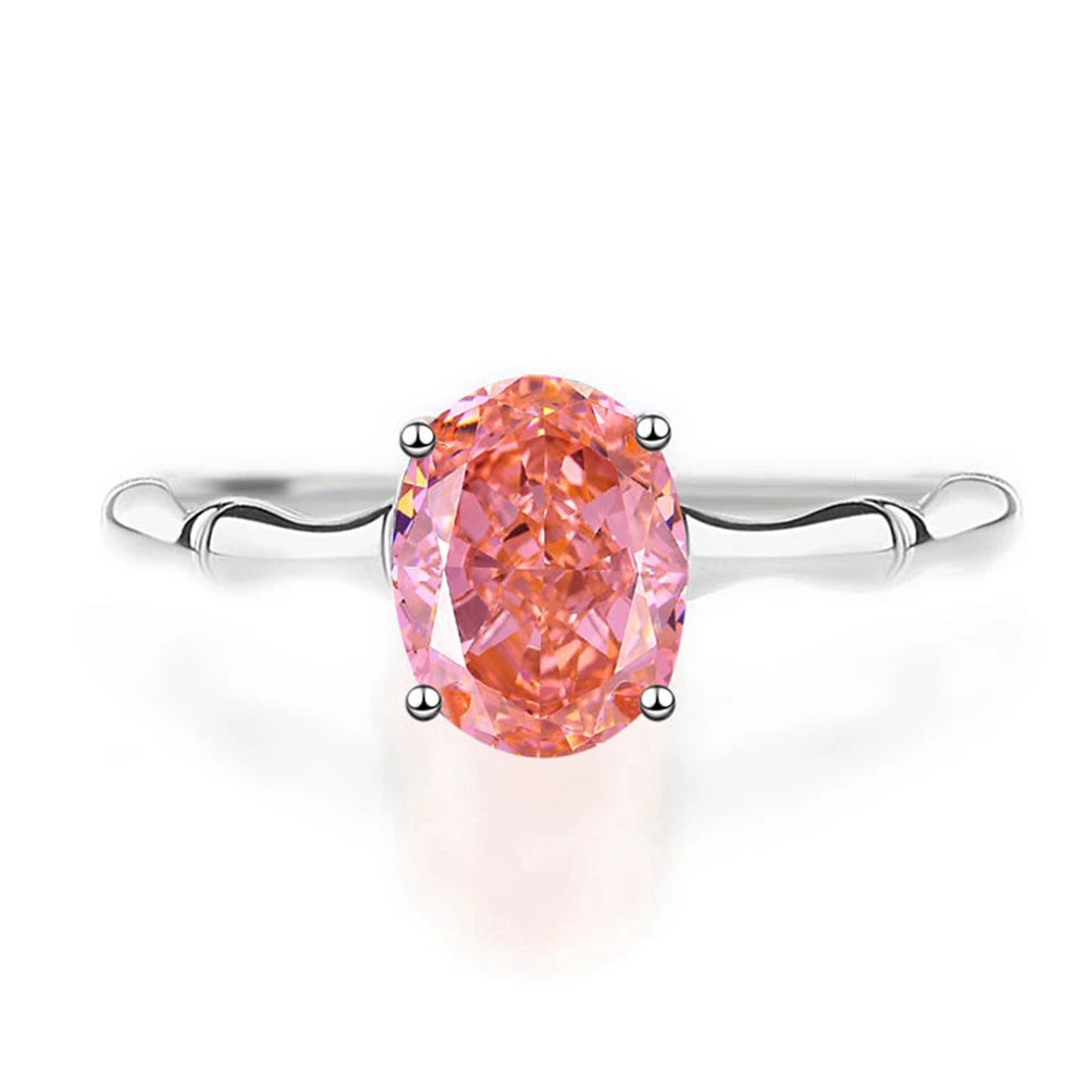 Silver band ring with an oval-cut pink-orange tourmaline stone, displayed against a deep red background from the Rossa collection.

