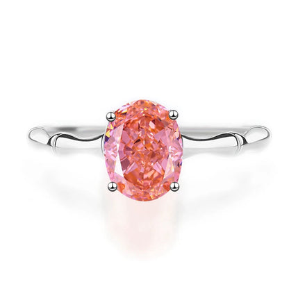Silver band ring with an oval-cut pink-orange tourmaline stone, displayed against a deep red background from the Rossa collection.

