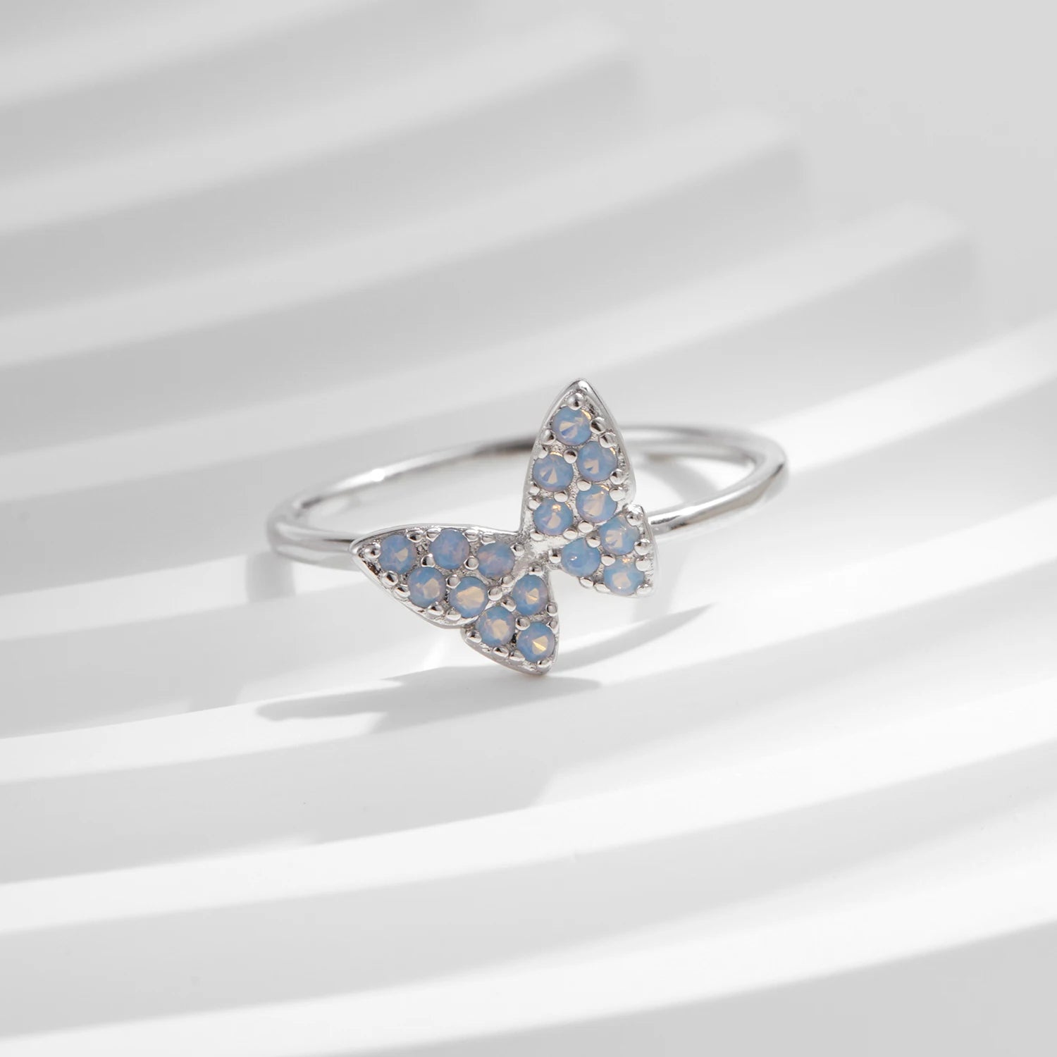 Sterling silver ring with a delicate butterfly shape inlaid with shimmering opal stones

