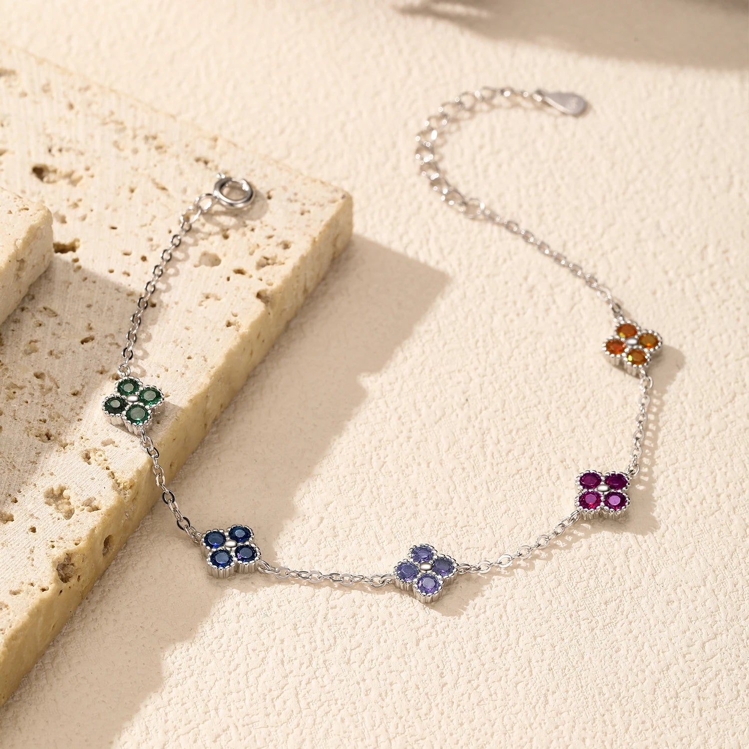 Silver bracelet with multicoloured gemstone clusters in floral shapes.

