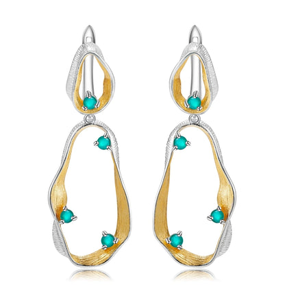 Dangling earrings with flowing gold and silver forms set with turquoise-colored stones

