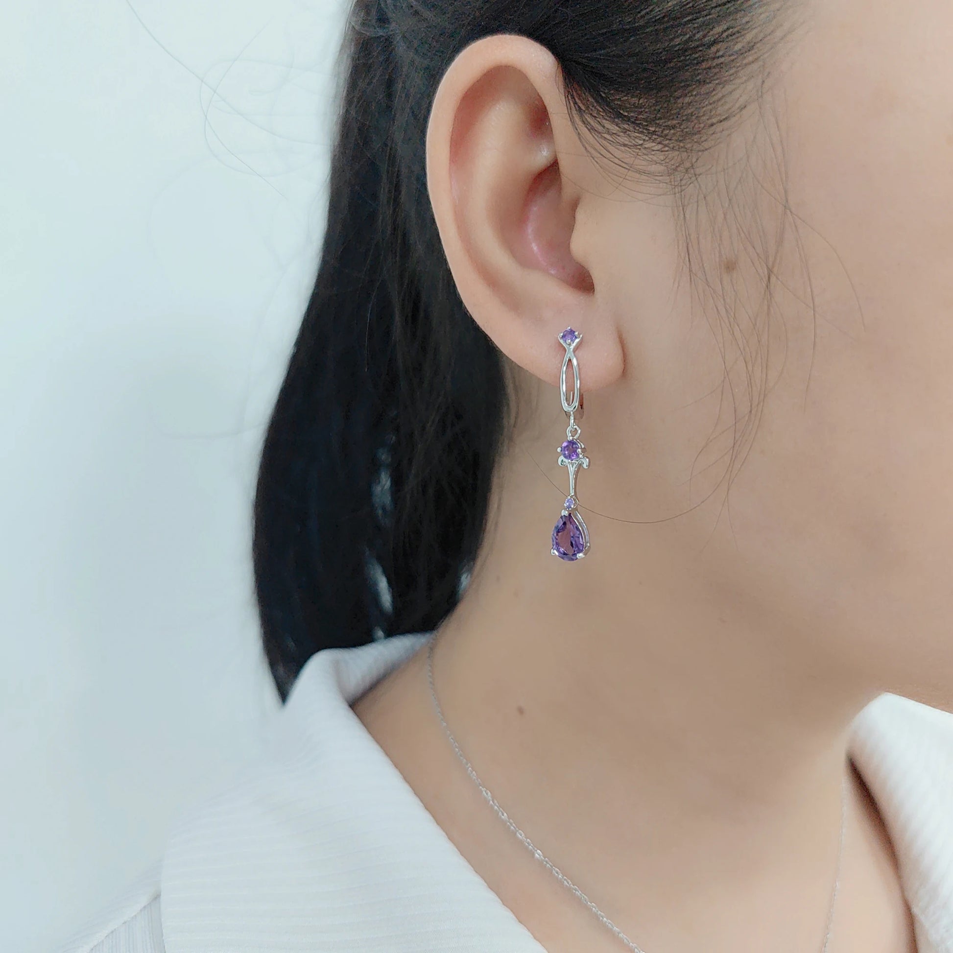 Dangling silver earrings with purple teardrop stones and delicate swirl detailing

