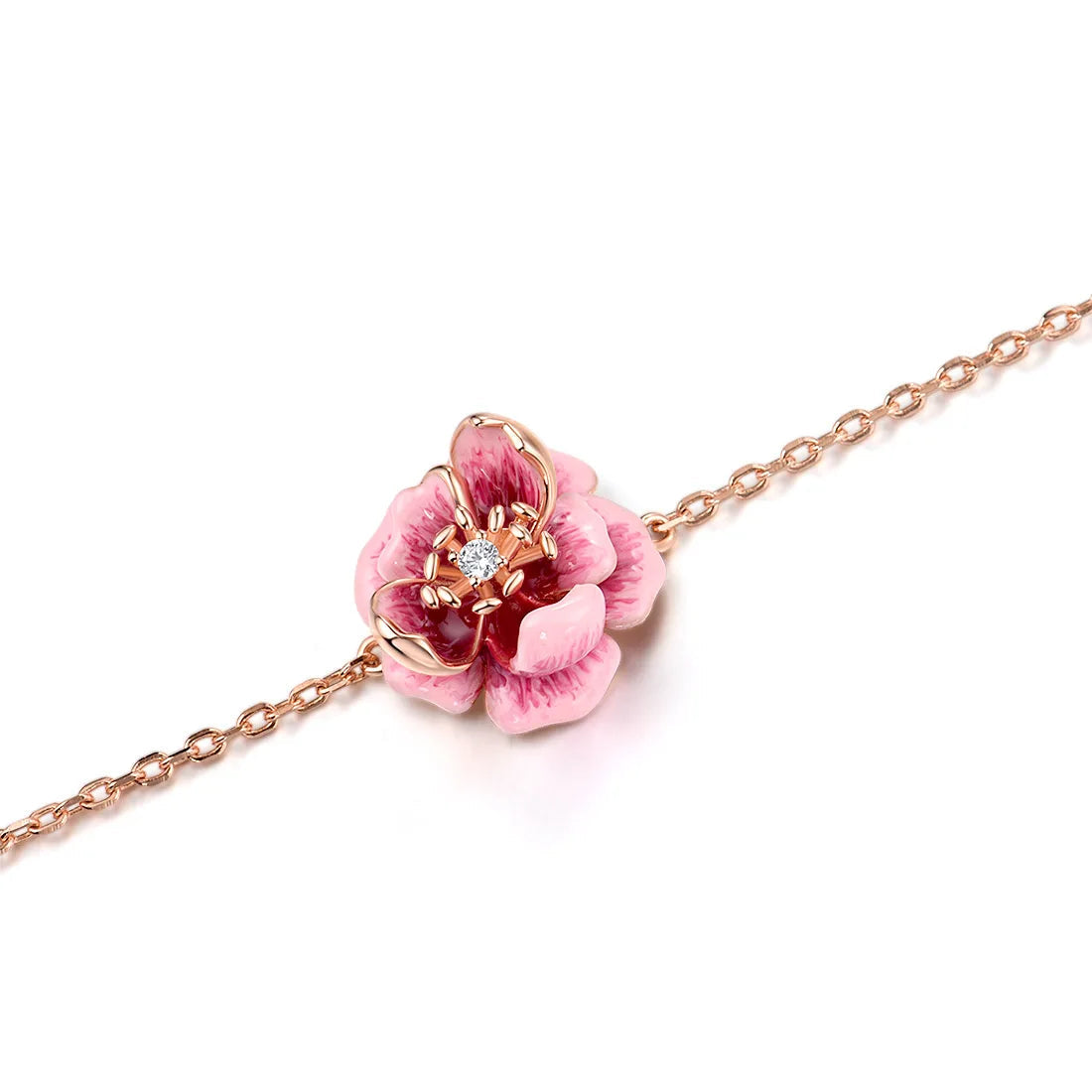 Anemone bracelet with a delicate chain and a central pink flower charm detailed with enamel and a sparkling center stone.

