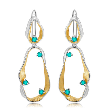 Dangling earrings with flowing gold and silver forms set with turquoise-colored stones

