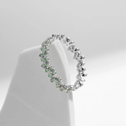 Sterling silver floral band ring with light green enamel petals and tiny diamond accents.

