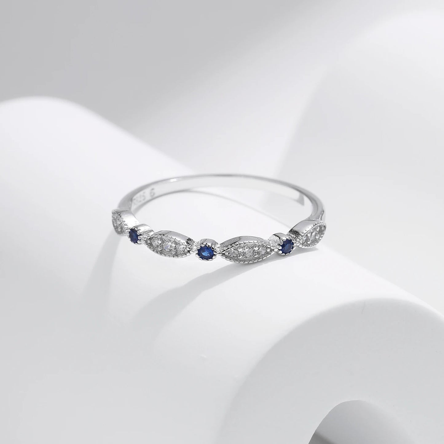 Sterling silver band with alternating marquise shapes and small round blue and clear stones

