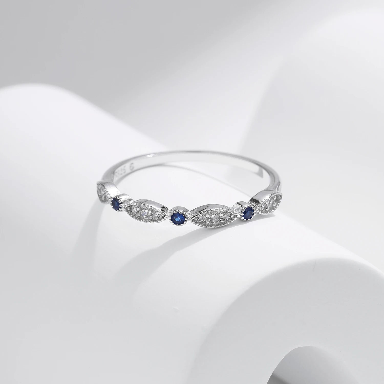Sterling silver band with alternating marquise shapes and small round blue and clear stones

