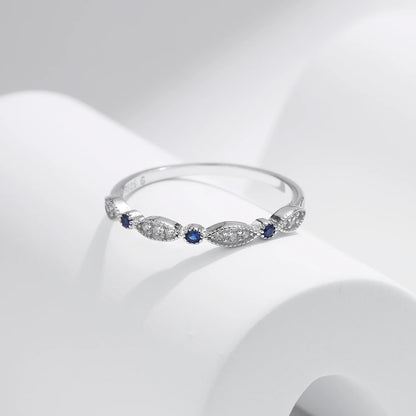 Sterling silver band with alternating marquise shapes and small round blue and clear stones

