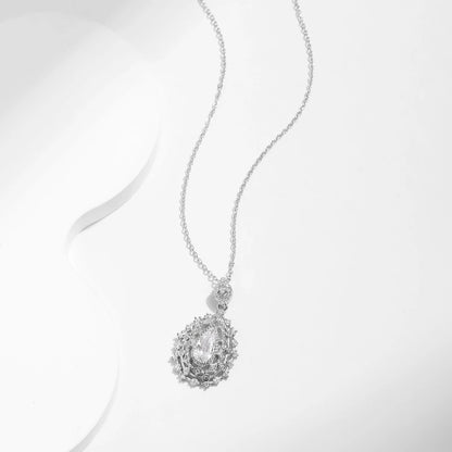 Ornate silver necklace with an intricate teardrop pendant, featuring a central pear-cut white gemstone, part of the Bianco Nero collection.

