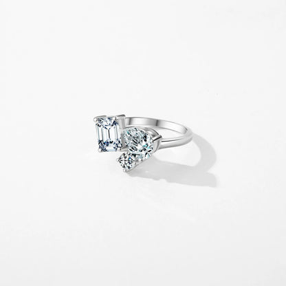 Silver ring with a mix of emerald, pear, and round-cut clear stones in an asymmetrical setting

