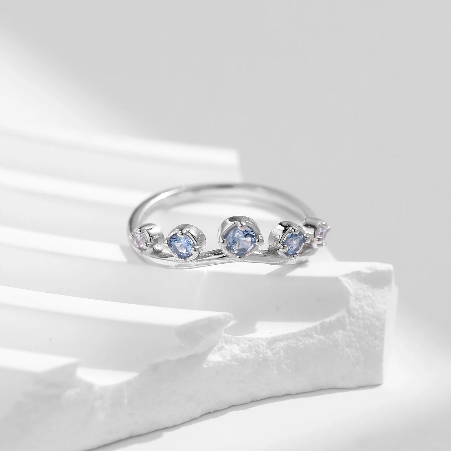Sterling silver ring with six graduated light blue and lavender stones set in a tiara-like arc

