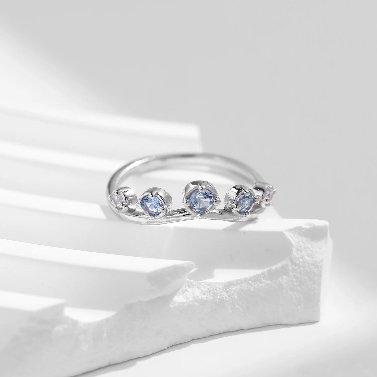 Sterling silver ring with six graduated light blue and lavender stones set in a tiara-like arc

