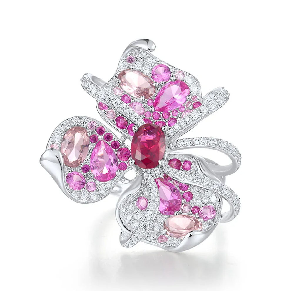Lalicata ring shaped like an abstract floral design, adorned with pink and red gemstones set in polished silver.

