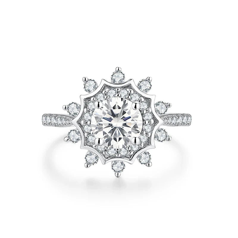 Silver ring with a radiant round central stone surrounded by a starburst of smaller stones, creating a layered floral effect.

