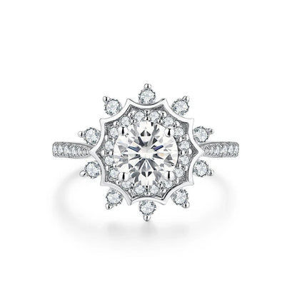 Silver ring with a radiant round central stone surrounded by a starburst of smaller stones, creating a layered floral effect.

