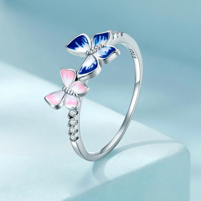 Delicate silver ring with pink and blue enamel butterflies and small white stones

