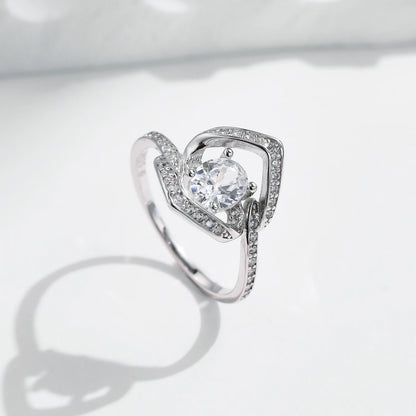 Silver ring with a central round white stone encircled by two asymmetrical open square-shaped bands encrusted with smaller stones.


