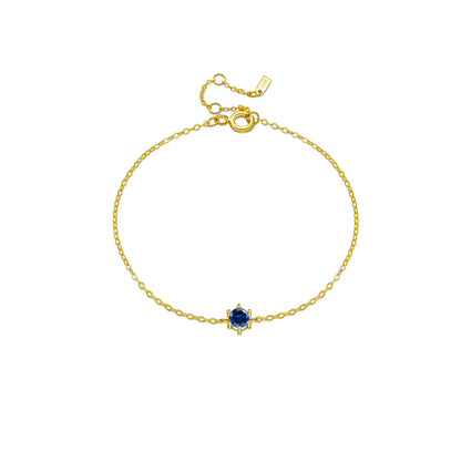 Delicate silver chain bracelet with a single round deep blue gemstone in a minimalist prong setting