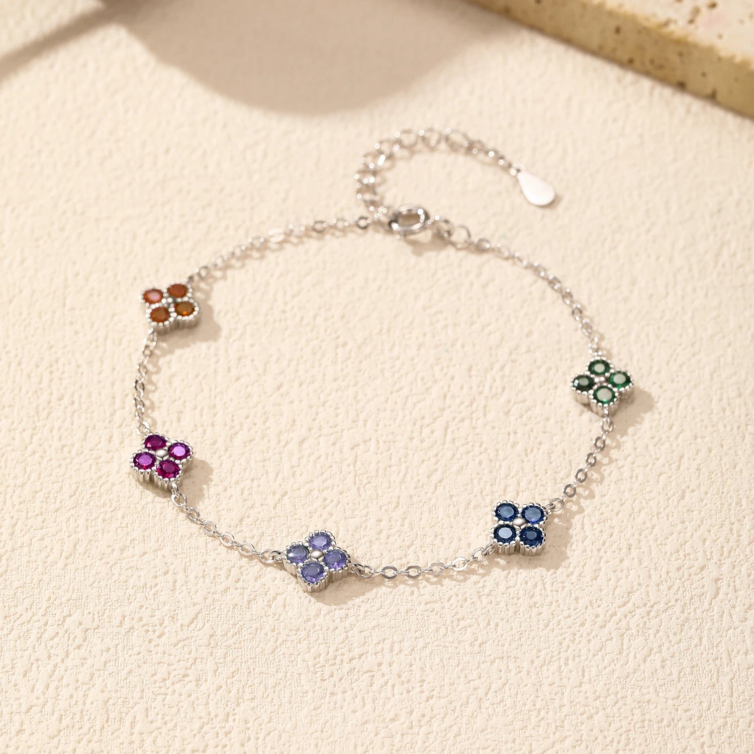 Silver bracelet with multicoloured gemstone clusters in floral shapes.

