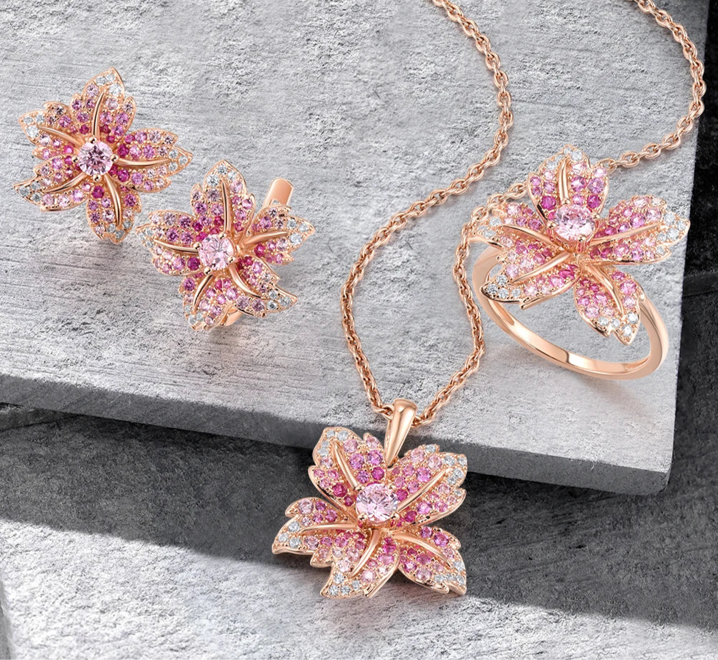 Giglio Rosa jewelry set featuring flower-shaped rose gold pieces with pink and white pavé stones, including ring, earrings, and pendant.

