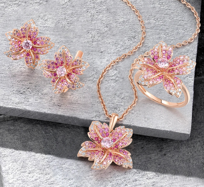 Giglio Rosa jewelry set featuring flower-shaped rose gold pieces with pink and white pavé stones, including ring, earrings, and pendant.

