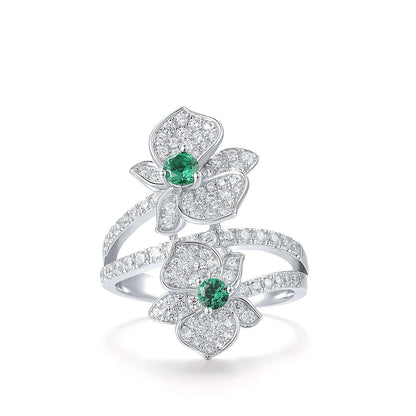 Sterling silver ring with twin pavé-set floral forms and vivid green center stones

