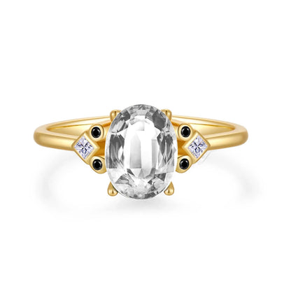 Gold ring with large oval brown gemstone and black and white accent stones

