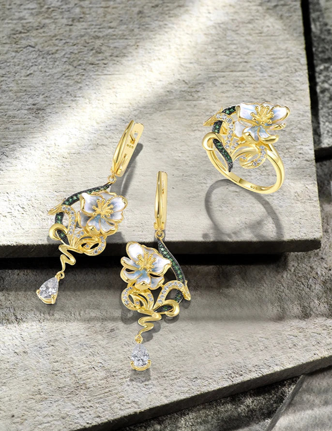 Nastro Verde jewelry set with green-accented gold-tone earrings and ring featuring delicate white flowers from the Verde collection.

