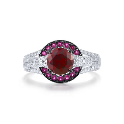 Silver ring with a large round red center stone, surrounded by a crescent of smaller pink stones and pavé white accents on a split band.


