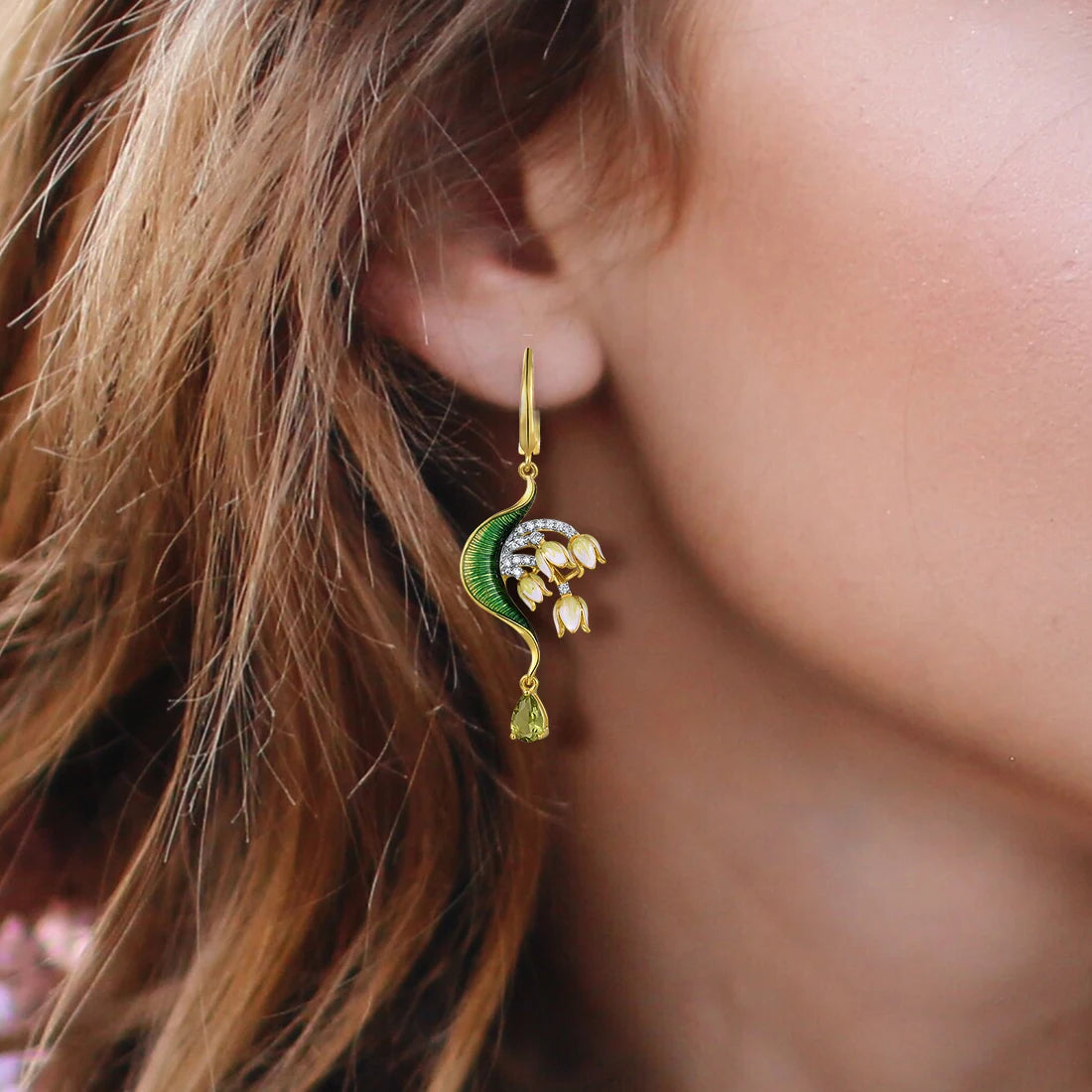 Gold drop earrings with curved green enamel leaves and cascading pink floral buds accented by pavé stones and teardrop gems

