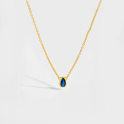 Gold chain necklace featuring a pear-shaped deep blue gemstone in a bezel setting