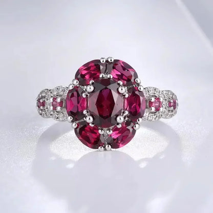 Silver ring featuring a bold cluster of deep red oval gemstones, framed by smaller accents, from the Rossa Collection.

