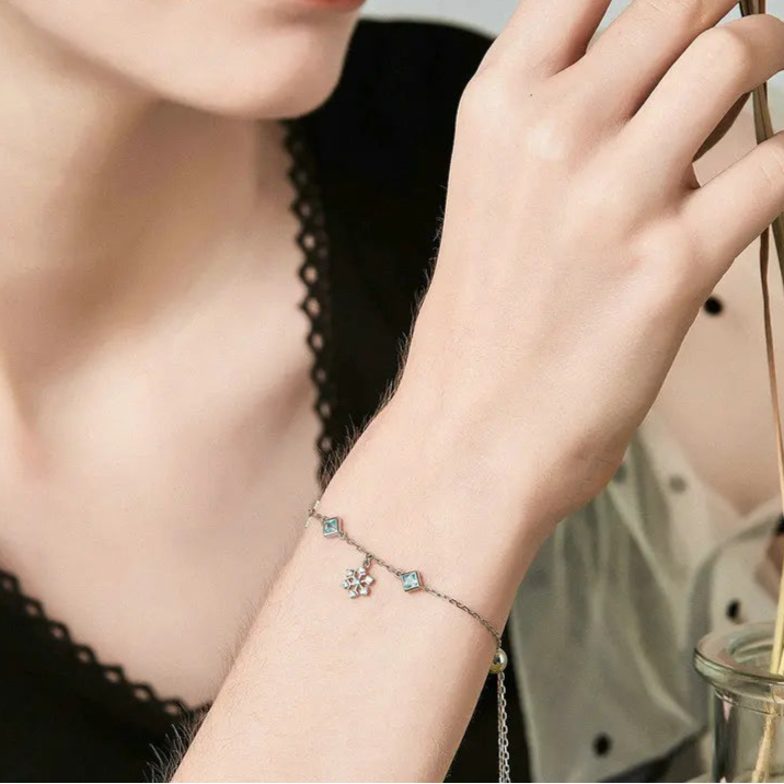 Delicate silver adjustable bracelet with blue square-cut stones and snowflake charms

