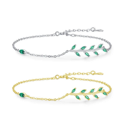 Gold chain bracelet with a delicate green leaf branch design.

