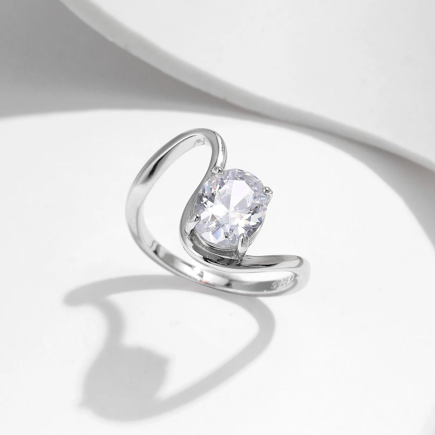 Open silver ring with a triangular wrap design, featuring a prominent oval white stone at its center, from the Bianco Nero collection.

