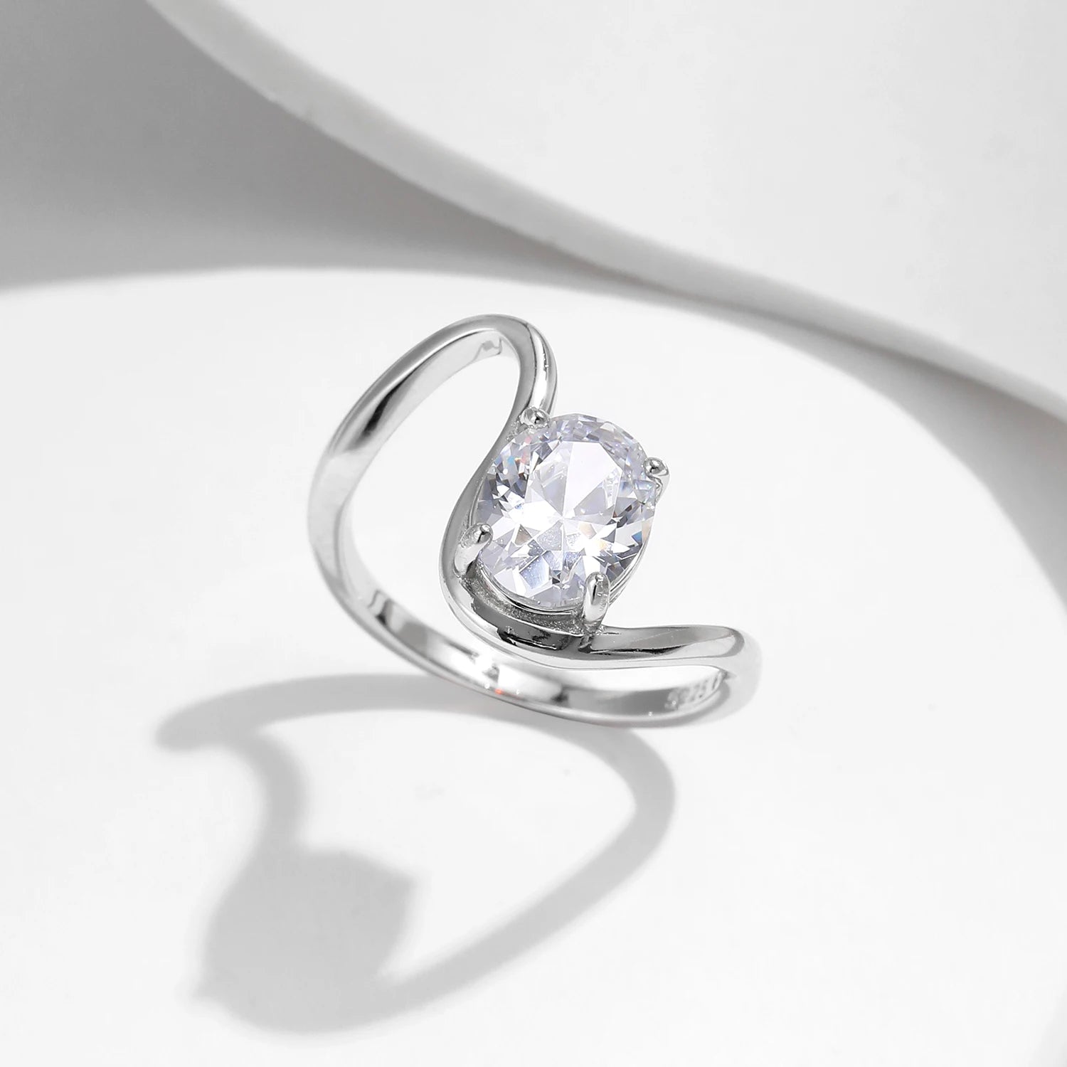Open silver ring with a triangular wrap design, featuring a prominent oval white stone at its center, from the Bianco Nero collection.

